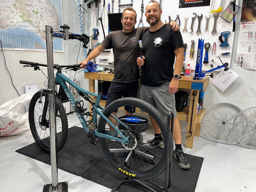 Two mechanics in the workshop with a mountain bike on a repair stand